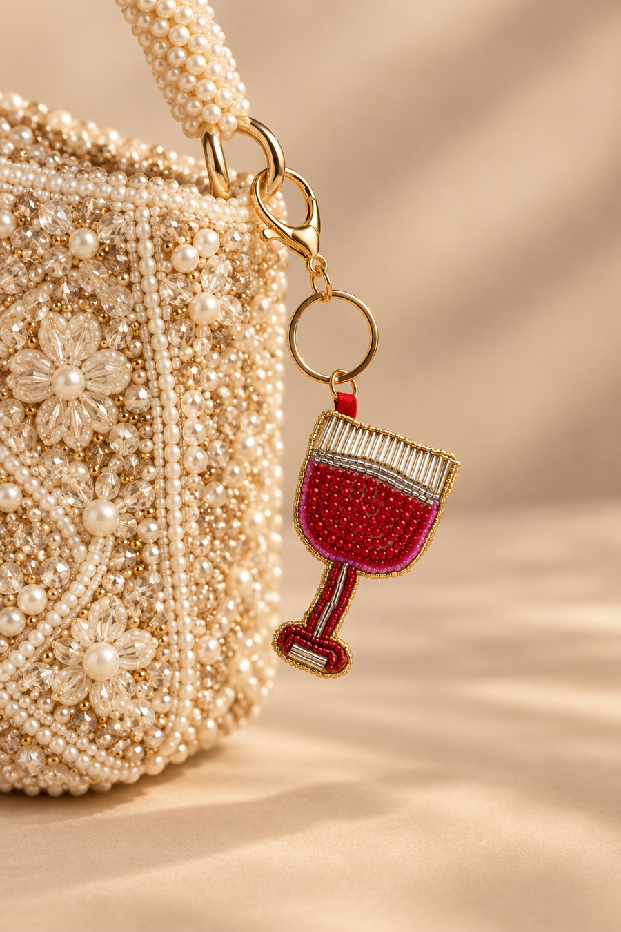 Red beaded wine glass keychain clipped on a pearl embellished handbag