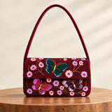 A burgundy beaded butterflies shoulder bag with a flap front.