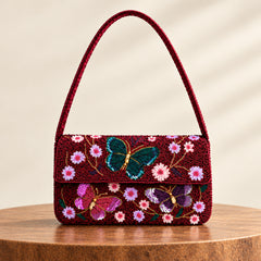 A burgundy beaded butterflies shoulder bag with a flap front.