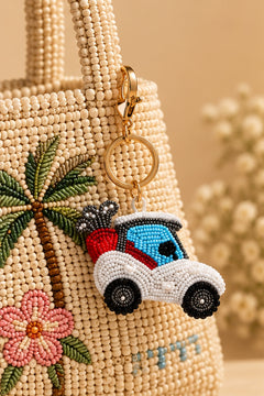 White and blue beaded golf cart keychain with red golf bag on a stone tray