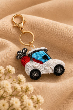 White and blue beaded golf cart keychain with red golf bag on a stone tray