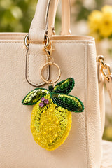 Yellow beaded lemon keychain with green sequin leaves on a stone tray